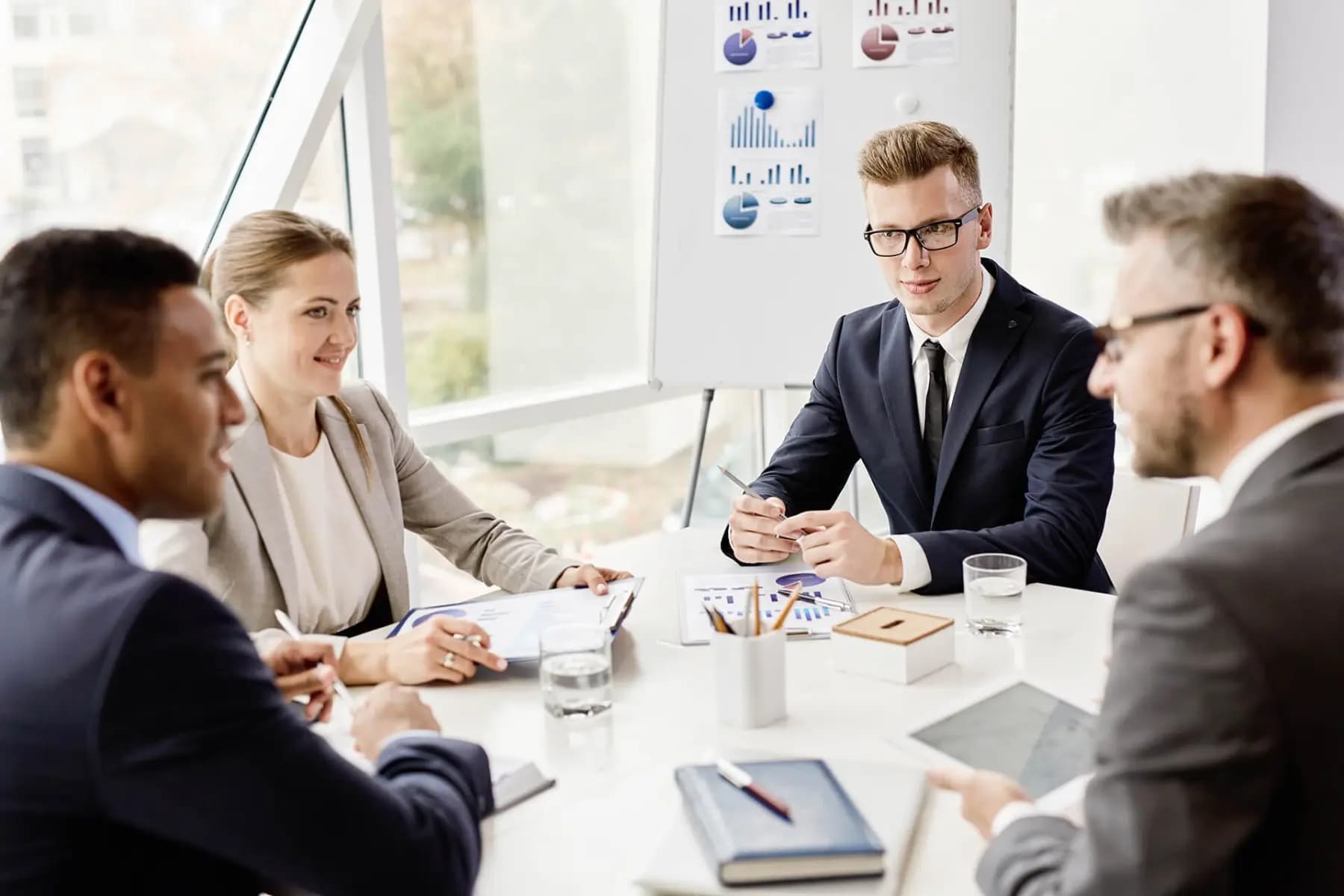 Vier Personen in Businesskleidung besprechen Diagramme an einem Konferenztisch